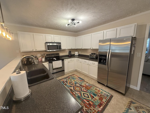 kitchen featuring dark countertops, white cabinetry, stainless steel appliances, and a sink