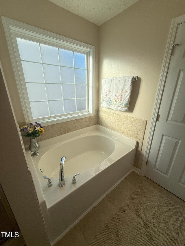 bathroom featuring tile patterned flooring, a textured ceiling, and a bath