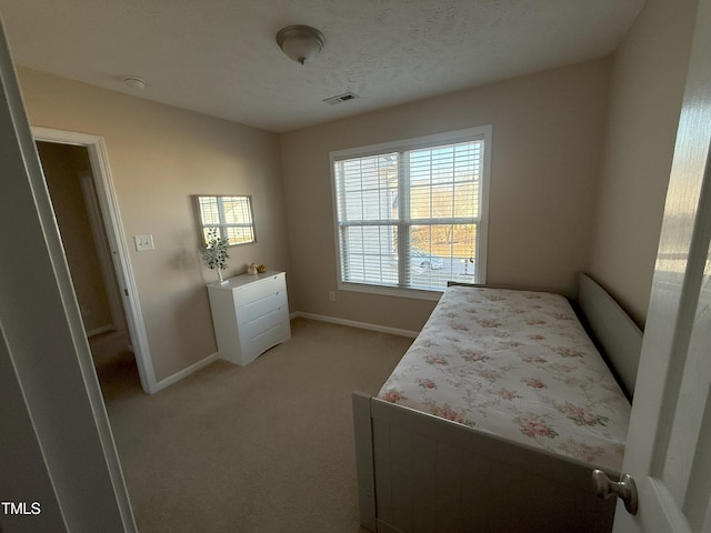 bedroom with a textured ceiling, carpet flooring, visible vents, and baseboards