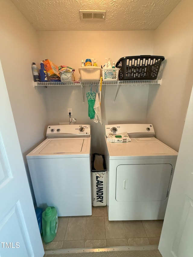 laundry room with a textured ceiling, tile patterned flooring, laundry area, visible vents, and washing machine and clothes dryer