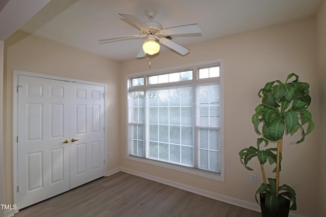 interior space with a ceiling fan, a closet, baseboards, and wood finished floors