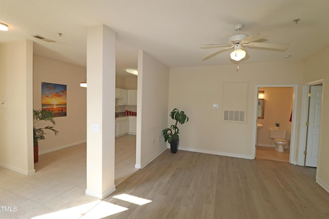 spare room with a ceiling fan, light wood-type flooring, visible vents, and baseboards