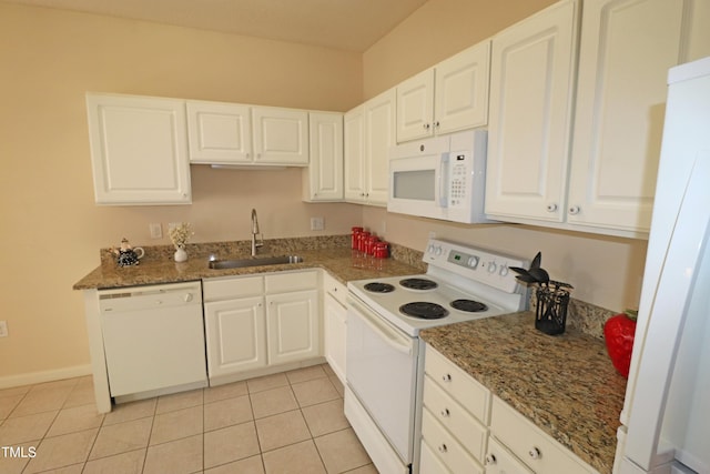 kitchen featuring white appliances, dark stone countertops, a sink, and white cabinets