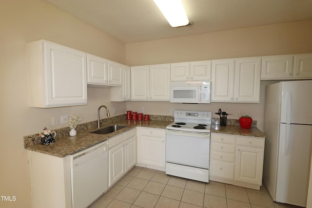 kitchen with stone counters, light tile patterned floors, white cabinets, a sink, and white appliances