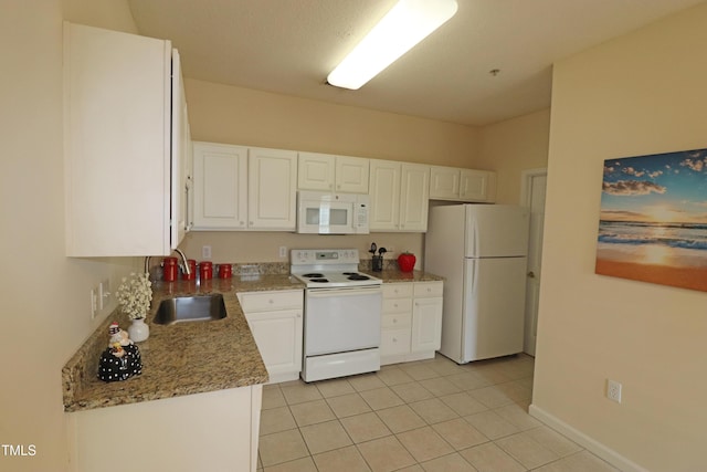 kitchen featuring white cabinets, a sink, light tile patterned flooring, white appliances, and baseboards