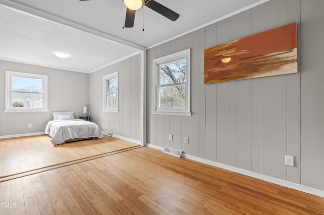 unfurnished bedroom with wood-type flooring, visible vents, baseboards, and ornamental molding