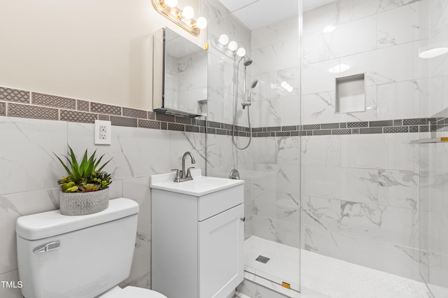 bathroom with vanity, a tile shower, toilet, and tile walls