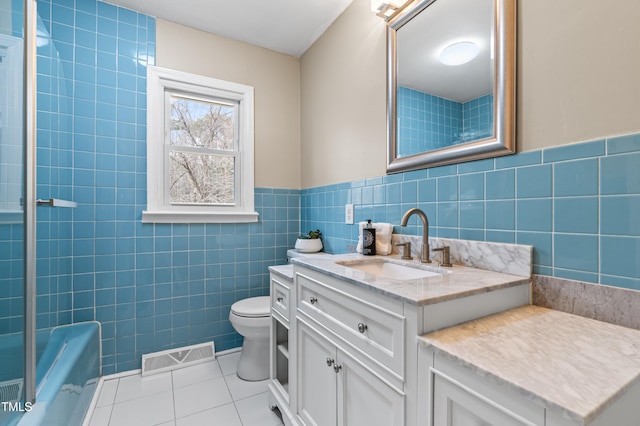 full bath featuring tile patterned flooring, toilet, vanity, visible vents, and tile walls