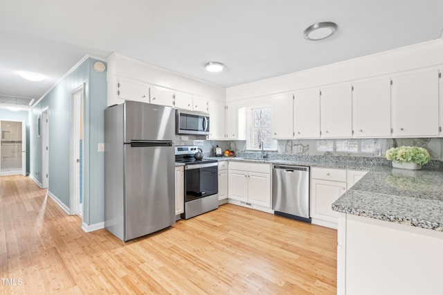 kitchen with appliances with stainless steel finishes, light wood-type flooring, and white cabinets