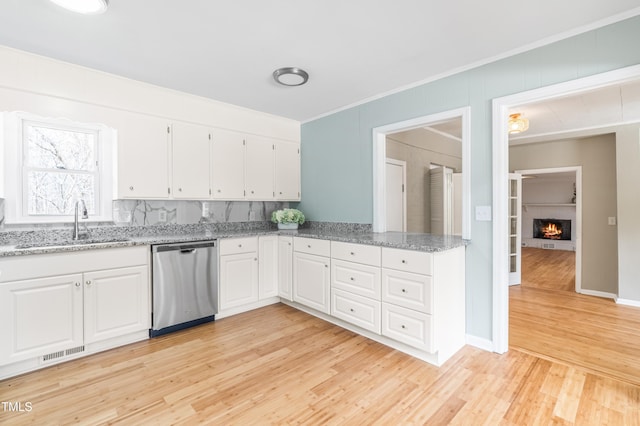 kitchen featuring crown molding, light wood-style floors, white cabinetry, a sink, and dishwasher