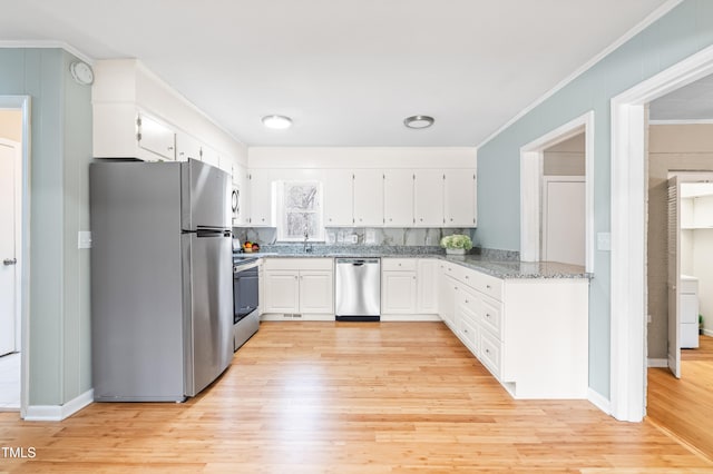 kitchen with white cabinets, ornamental molding, stainless steel appliances, light wood-style floors, and a sink