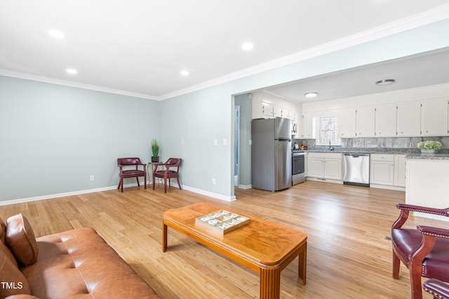 living room featuring crown molding, light wood-style flooring, and baseboards