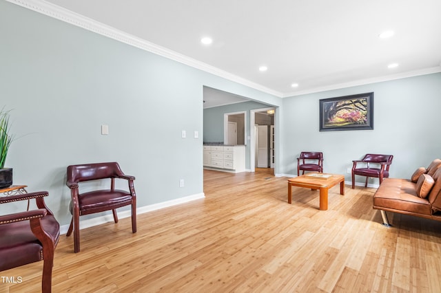 sitting room with light wood finished floors, baseboards, ornamental molding, and recessed lighting