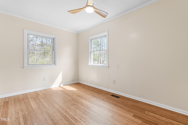 empty room with light wood-style floors, visible vents, ornamental molding, and baseboards