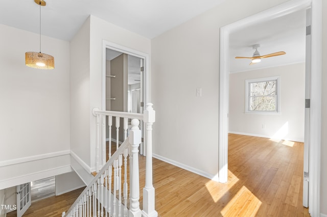 hallway with baseboards, an upstairs landing, and wood finished floors