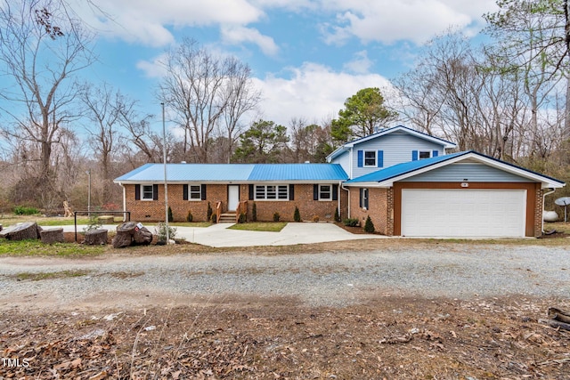 view of front of home featuring metal roof, brick siding, driveway, and an attached garage