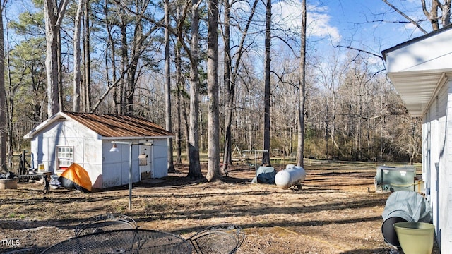 view of yard featuring an outbuilding, a storage unit, and a wooded view