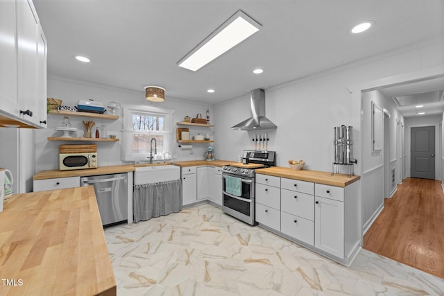 kitchen featuring stainless steel appliances, marble finish floor, wooden counters, wall chimney range hood, and open shelves