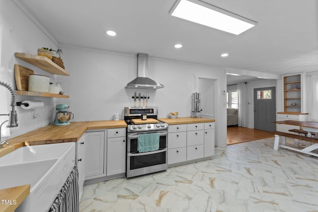 kitchen featuring wood counters, marble finish floor, wall chimney range hood, double oven range, and open shelves