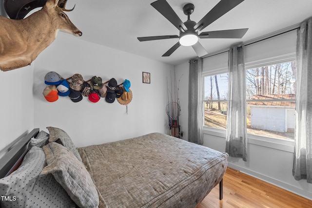 bedroom featuring a ceiling fan, light wood-style flooring, and baseboards