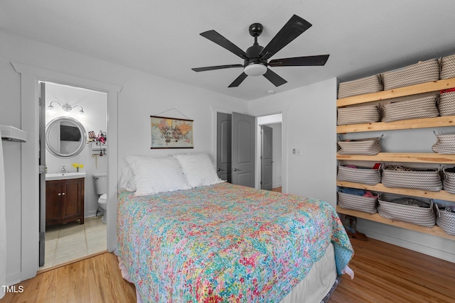 bedroom with a sink, ceiling fan, connected bathroom, and wood finished floors