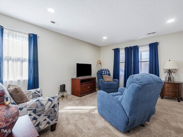 living room featuring plenty of natural light, light colored carpet, and visible vents