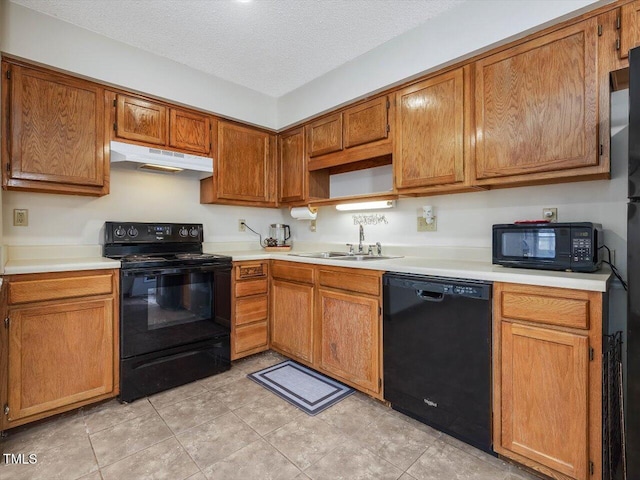 kitchen featuring black appliances, under cabinet range hood, a sink, a textured ceiling, and light countertops