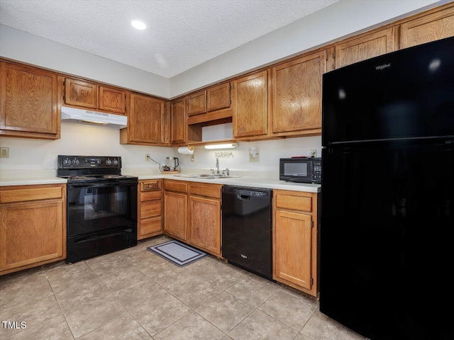 kitchen featuring black appliances, a sink, under cabinet range hood, a textured ceiling, and light countertops