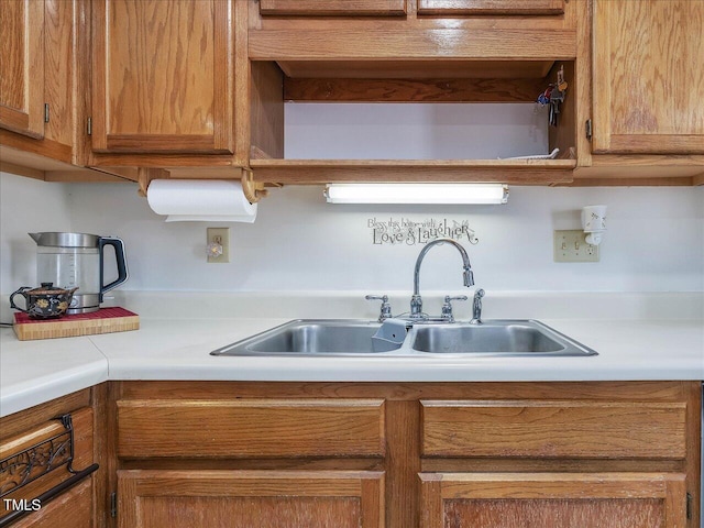 kitchen featuring light countertops, brown cabinetry, and a sink