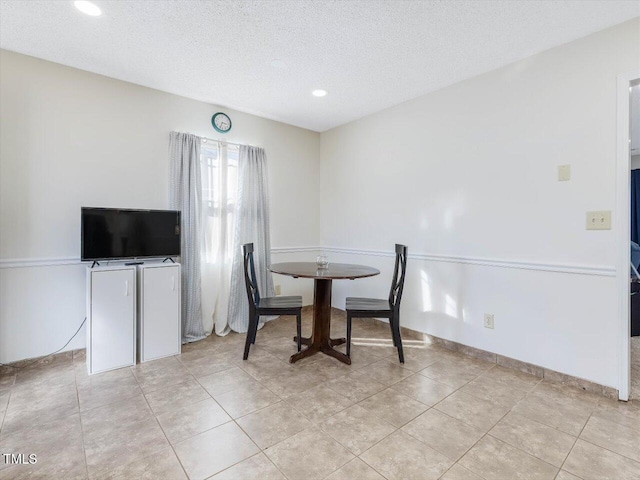 dining area with light tile patterned floors, baseboards, and a textured ceiling