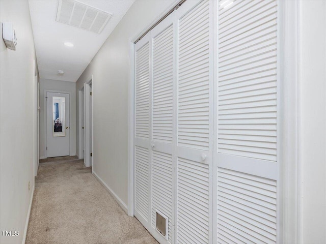 hall with visible vents, light carpet, and baseboards