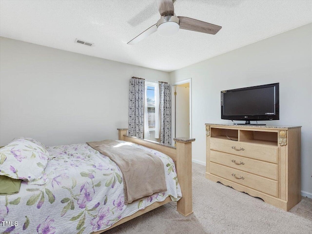 bedroom with a ceiling fan, light colored carpet, visible vents, and a textured ceiling