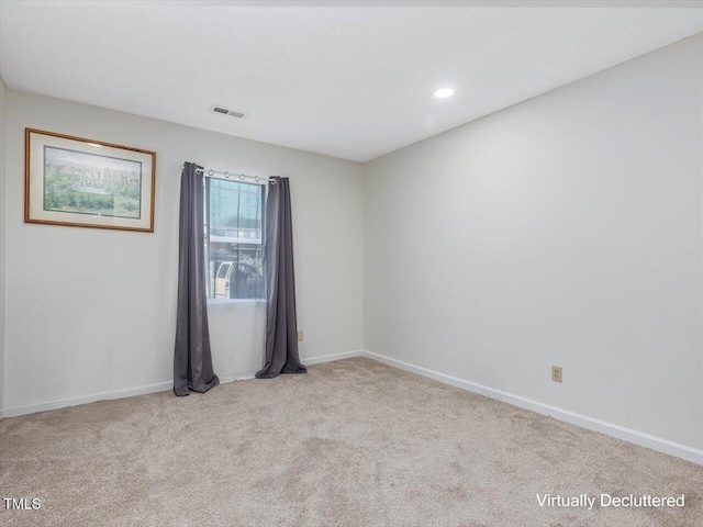 carpeted empty room with baseboards, visible vents, and a textured ceiling