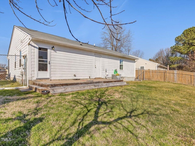 rear view of house with a deck, fence, and a lawn