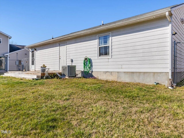 rear view of property with a yard, central AC unit, and fence