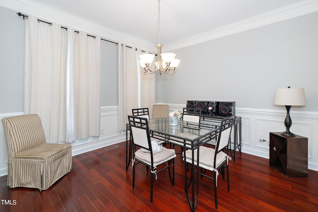 dining room with a chandelier, crown molding, a decorative wall, and wood finished floors