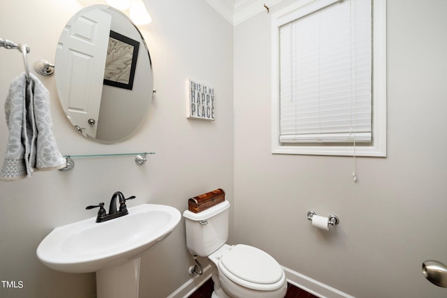 half bathroom with toilet, baseboards, and a sink