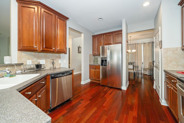 kitchen with tasteful backsplash, appliances with stainless steel finishes, brown cabinetry, dark wood-type flooring, and a sink