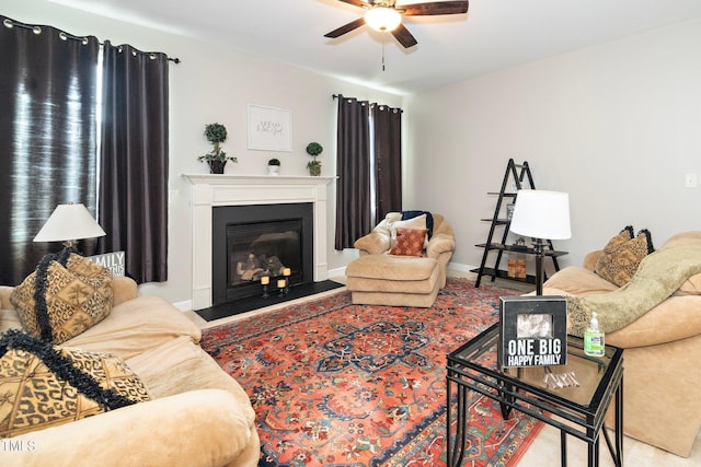 living room featuring a glass covered fireplace, a ceiling fan, and baseboards