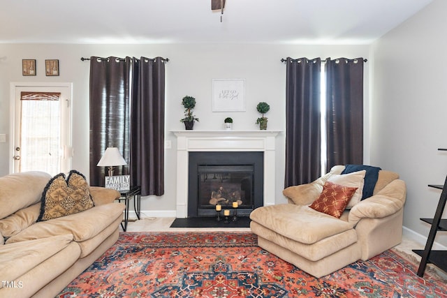 living area featuring a fireplace with flush hearth and baseboards