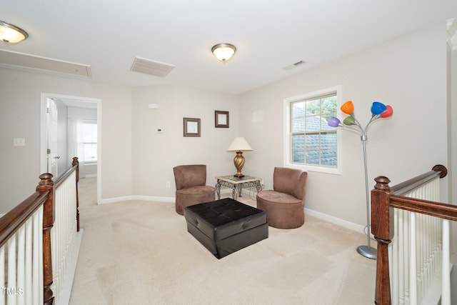 sitting room with attic access, baseboards, light colored carpet, and an upstairs landing