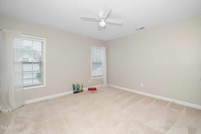 empty room with a healthy amount of sunlight, light colored carpet, visible vents, and baseboards