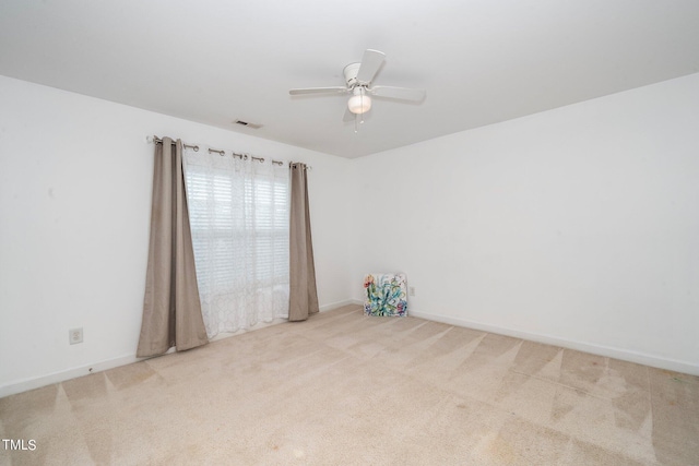 spare room with carpet floors, visible vents, ceiling fan, and baseboards