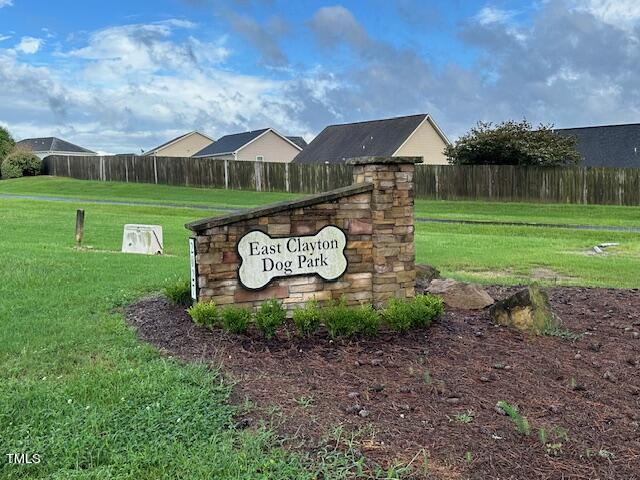 community / neighborhood sign with fence and a lawn