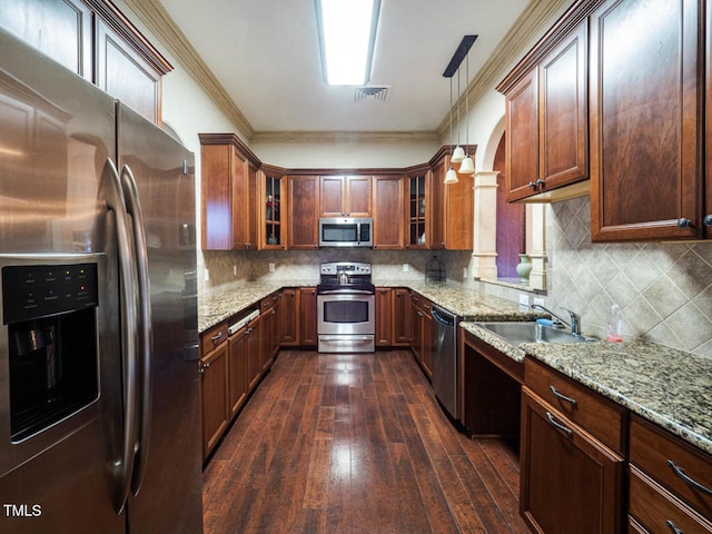 kitchen featuring visible vents, appliances with stainless steel finishes, light stone countertops, crown molding, and a sink