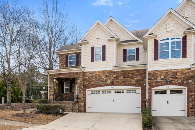 view of front of home with an attached garage, stone siding, and concrete driveway