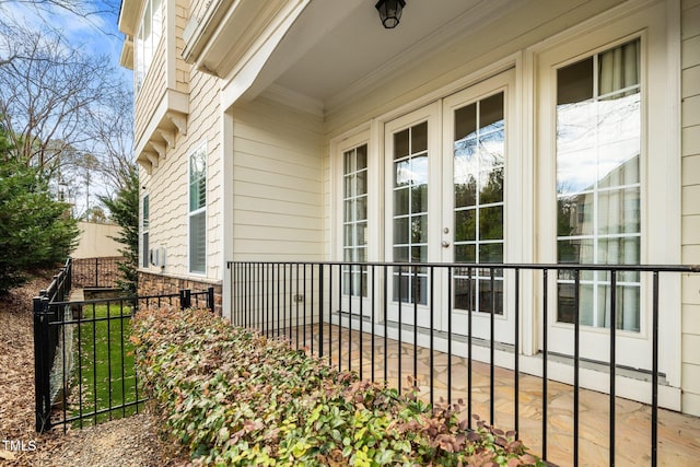 doorway to property featuring stone siding, french doors, and fence