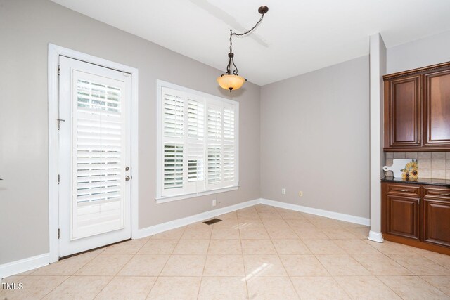 unfurnished dining area with light tile patterned floors, visible vents, and baseboards