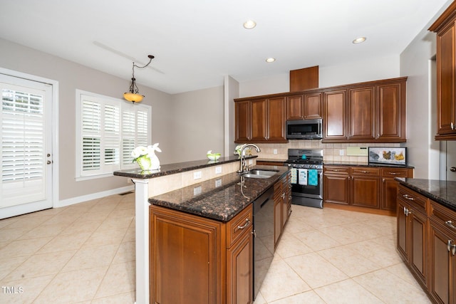 kitchen featuring light tile patterned floors, stainless steel appliances, decorative backsplash, a sink, and dark stone countertops