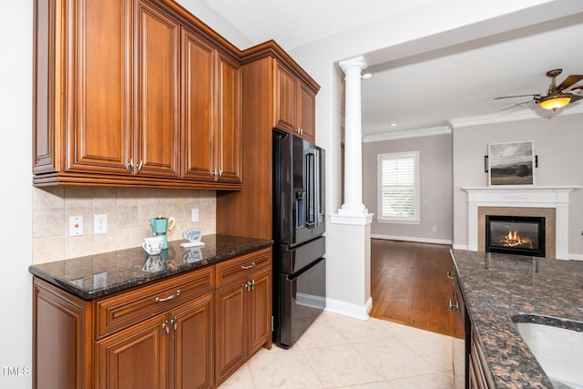 kitchen featuring light tile patterned floors, black fridge with ice dispenser, decorative columns, and brown cabinets